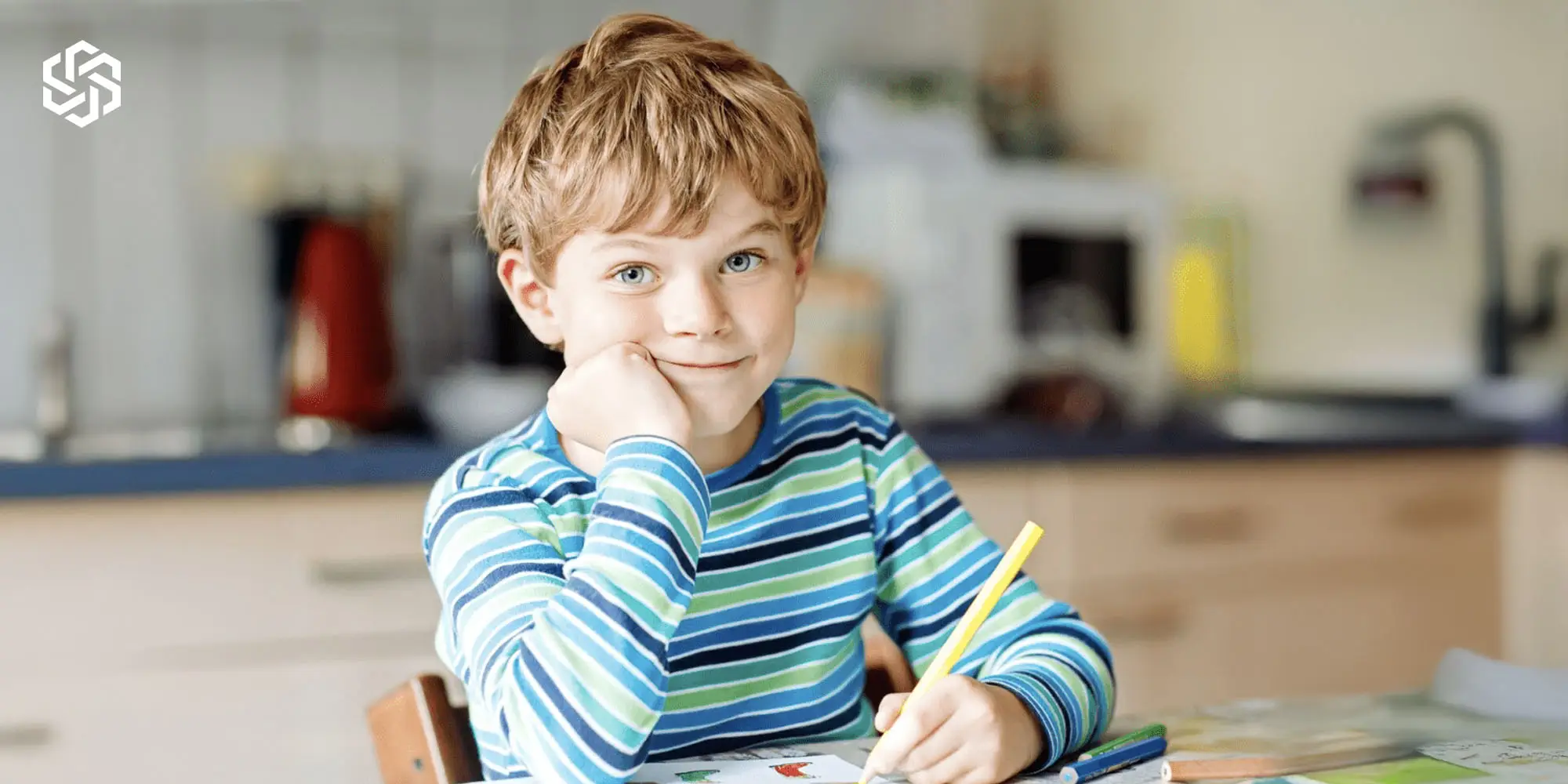 Young child smiling while working at a table, representing autism mental wellness treatment support for children in Lake Forest, Illinois