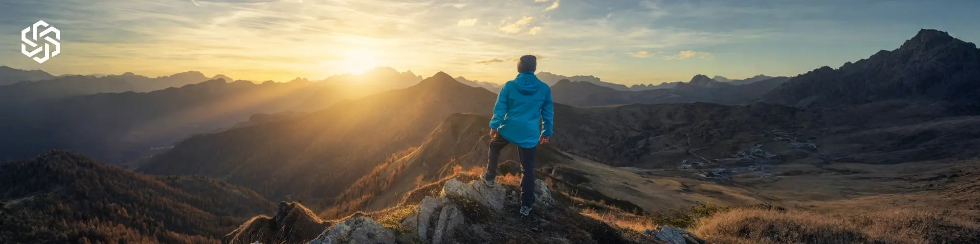 Man standing on mountain overlook at sunrise, representing progress and improved well-being during TRT