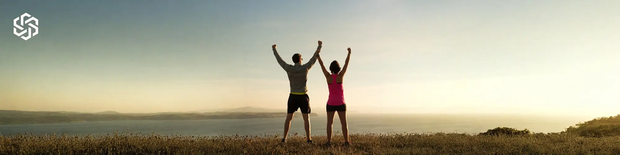 Two adults standing outdoors with arms raised, representing confidence and motivation through medically guided glp-1 therapy weight loss care