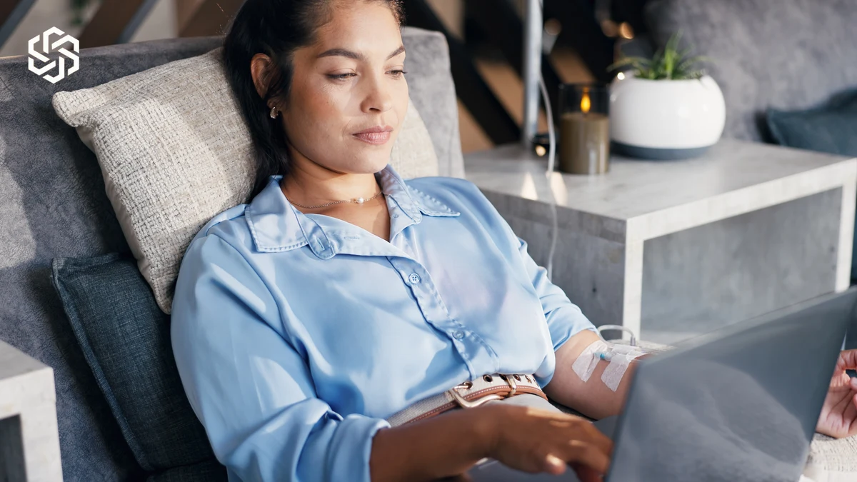 Woman relaxing in a lounge chair with a laptop during an IV therapy appointment
