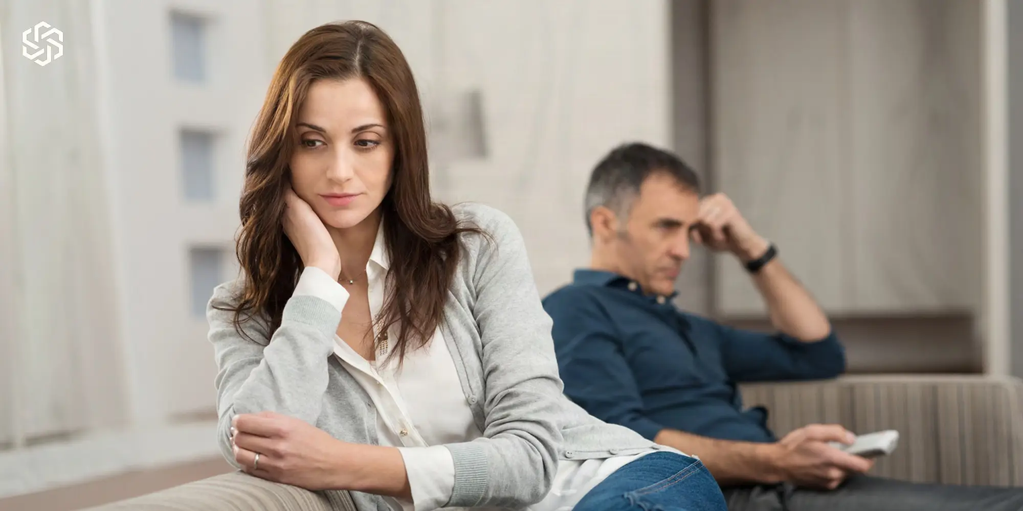 Woman sitting apart from her partner on a couch, looking distant