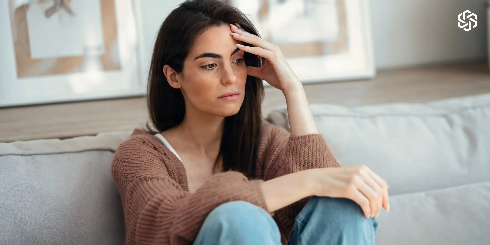 Stressed woman sitting on a couch with her hand on her forehead