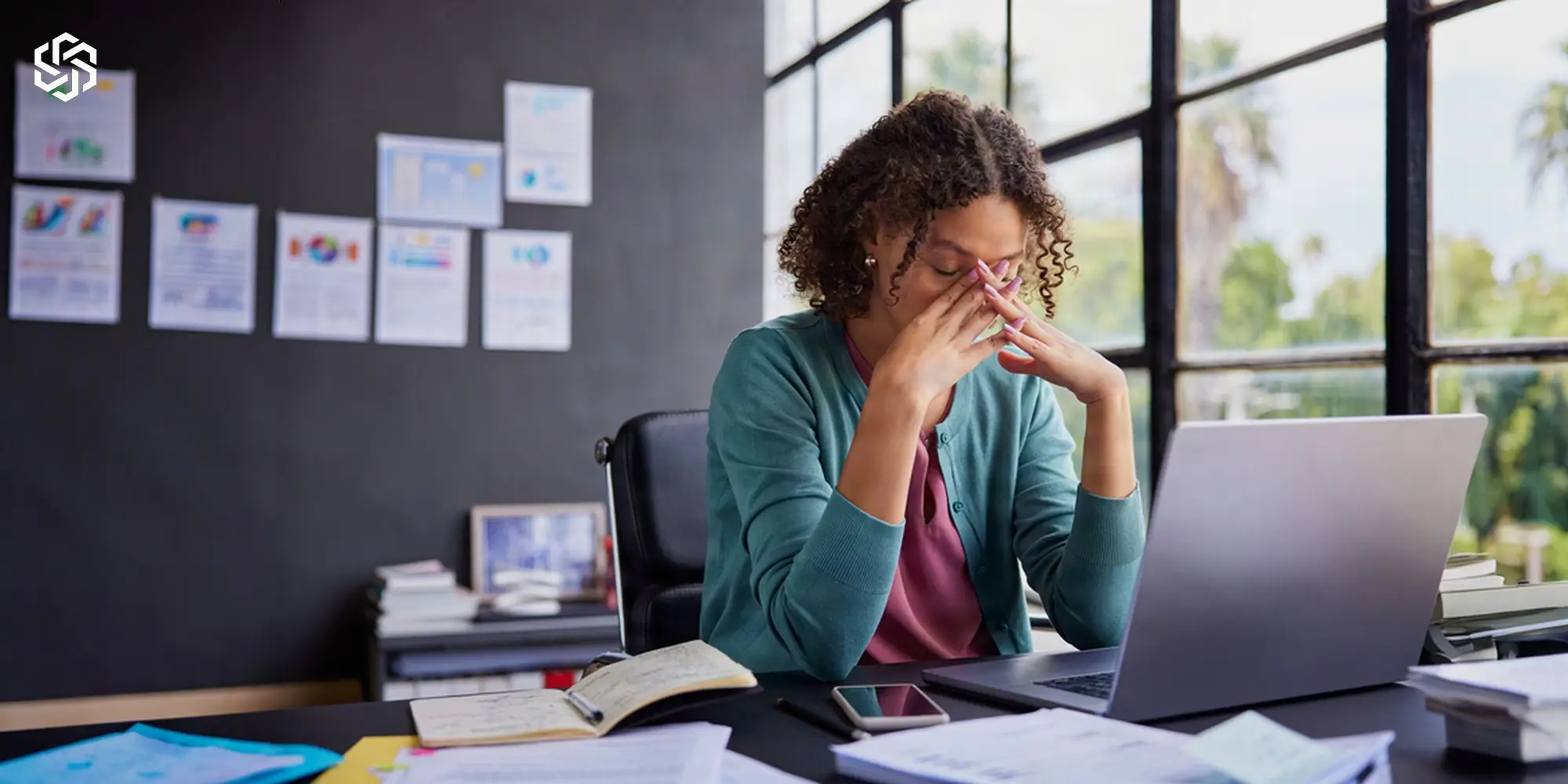 Tired woman at her desk rubbing her eyes in front of a laptop