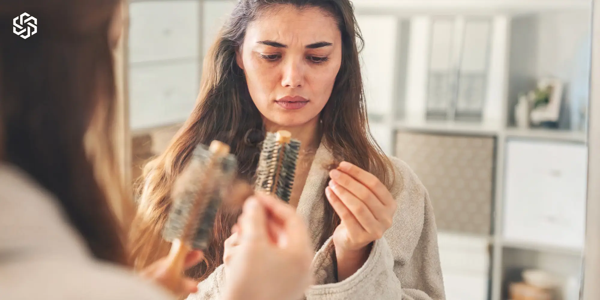 Woman looking with concern at hair caught in her brush