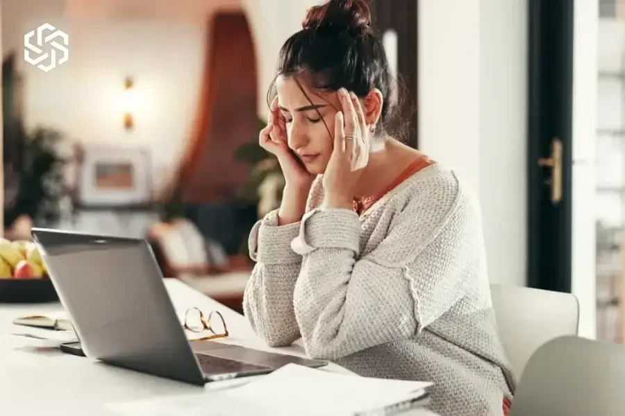 Woman with a headache working at her laptop