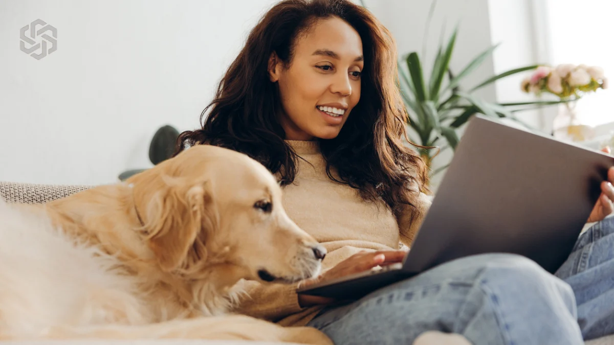 Woman working on a laptop at home with her dog
