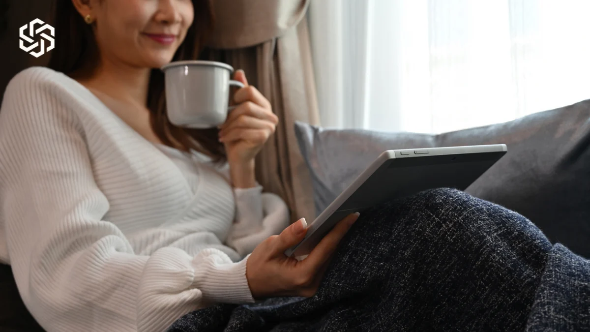 Woman relaxing under a blanket with a tablet