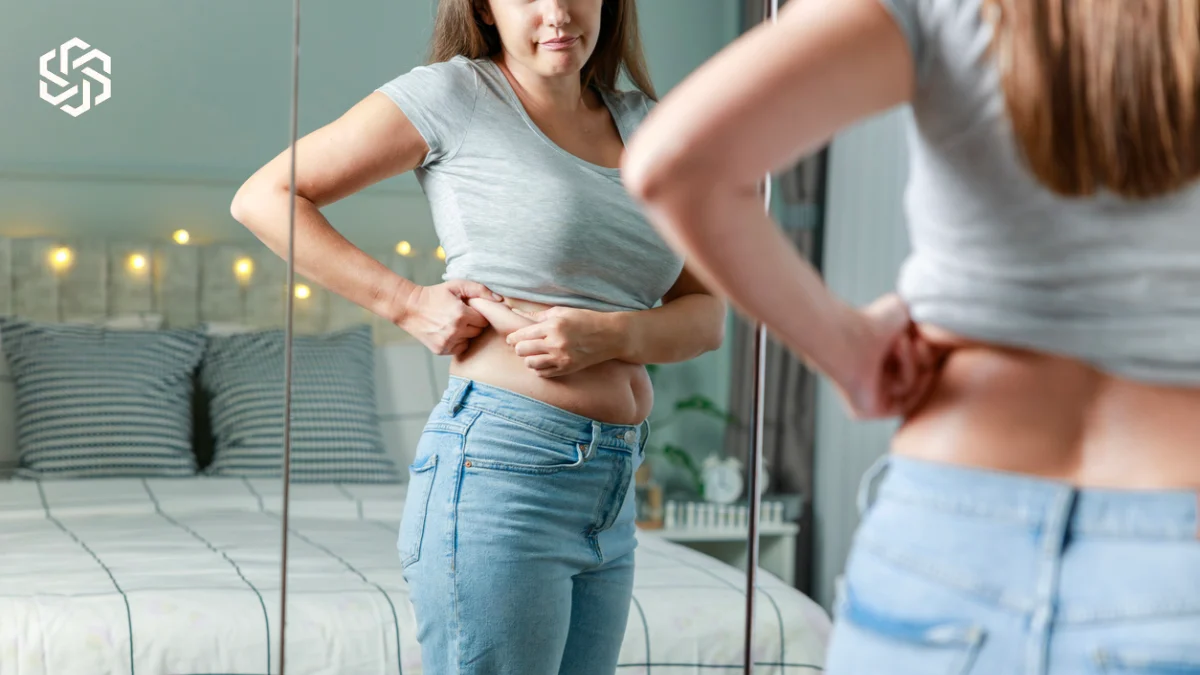 Woman looking at her midsection in a mirror