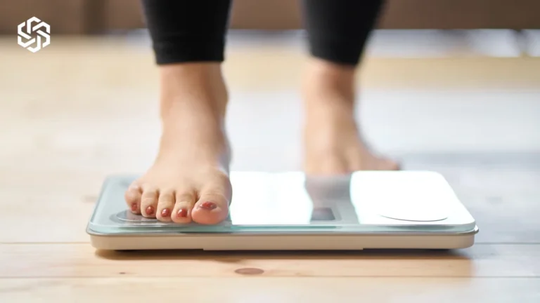 Feet on a bathroom scale, illustrating weight loss vs. fat loss