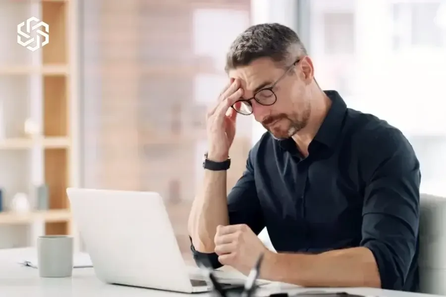 Man with a headache working at his laptop