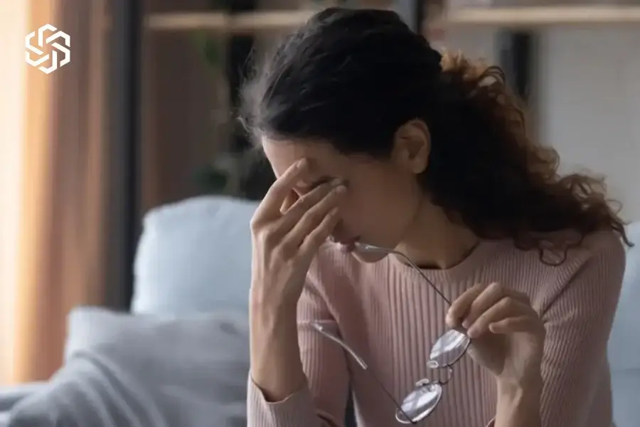 Woman with a headache removing her glasses