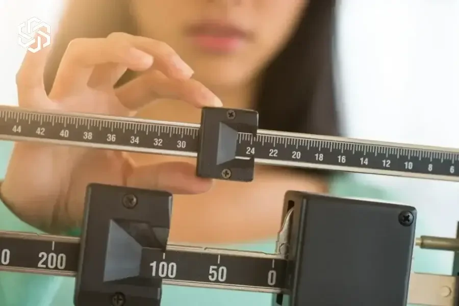 Woman adjusting a medical weight scale