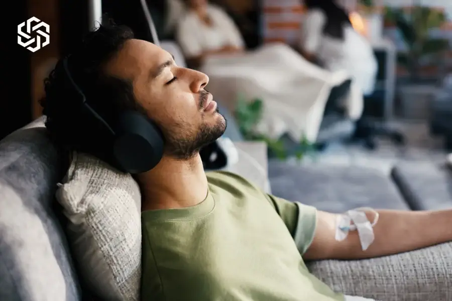 Man relaxing with headphones during an IV infusion