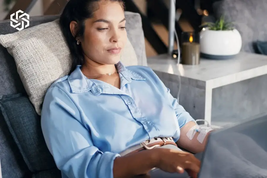 Woman relaxing in a lounge chair with a laptop during an IV session