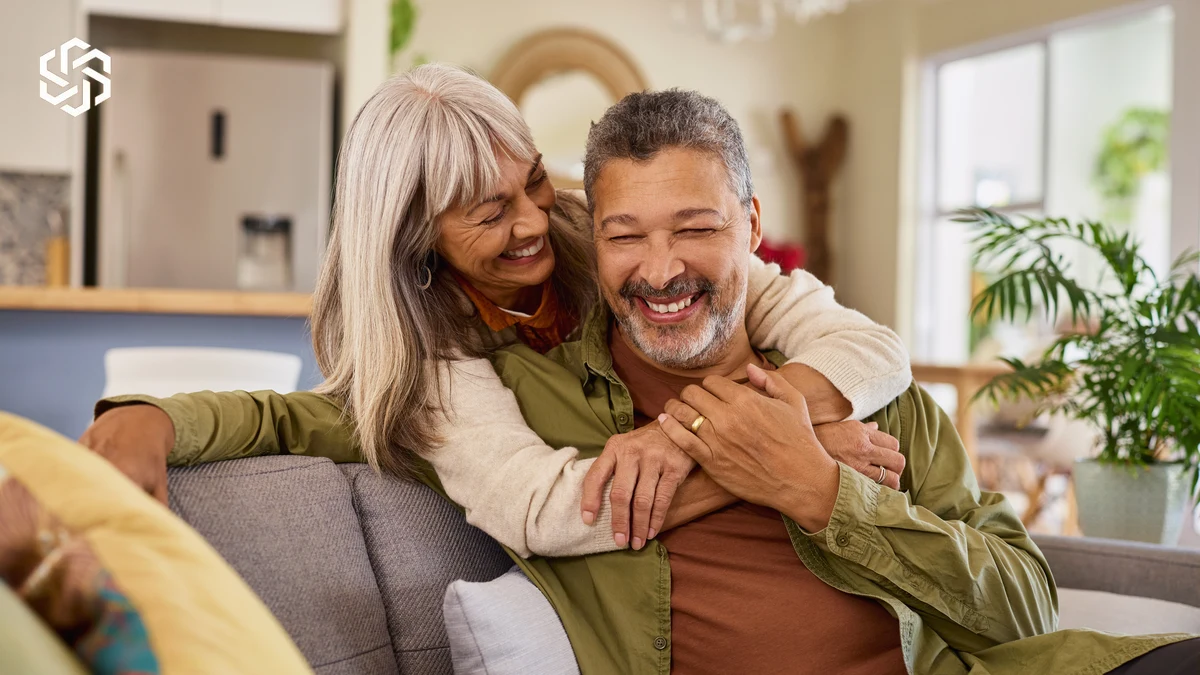 Smiling older couple embracing on a couch at home