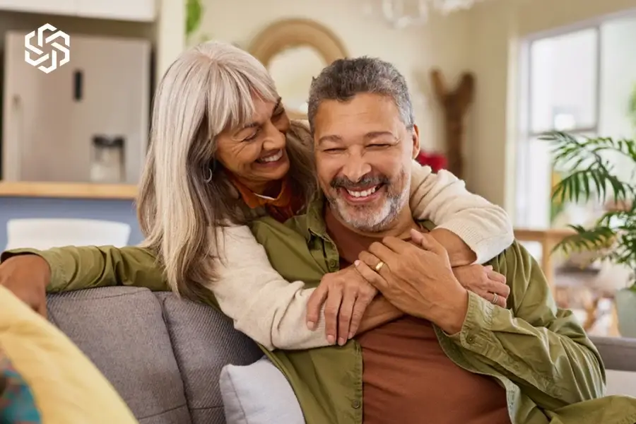 Smiling older couple embracing on a couch at home