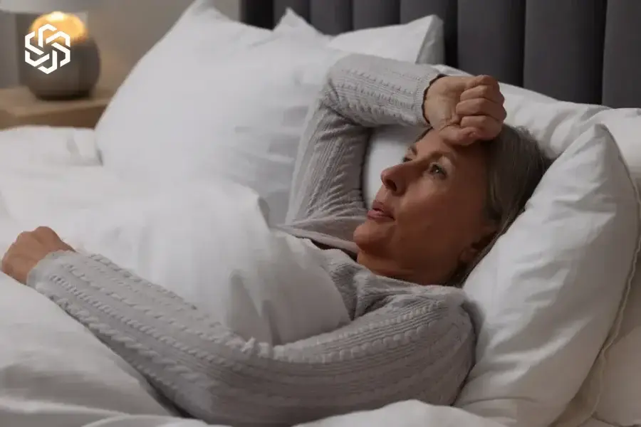Woman lying awake in bed feeling overheated