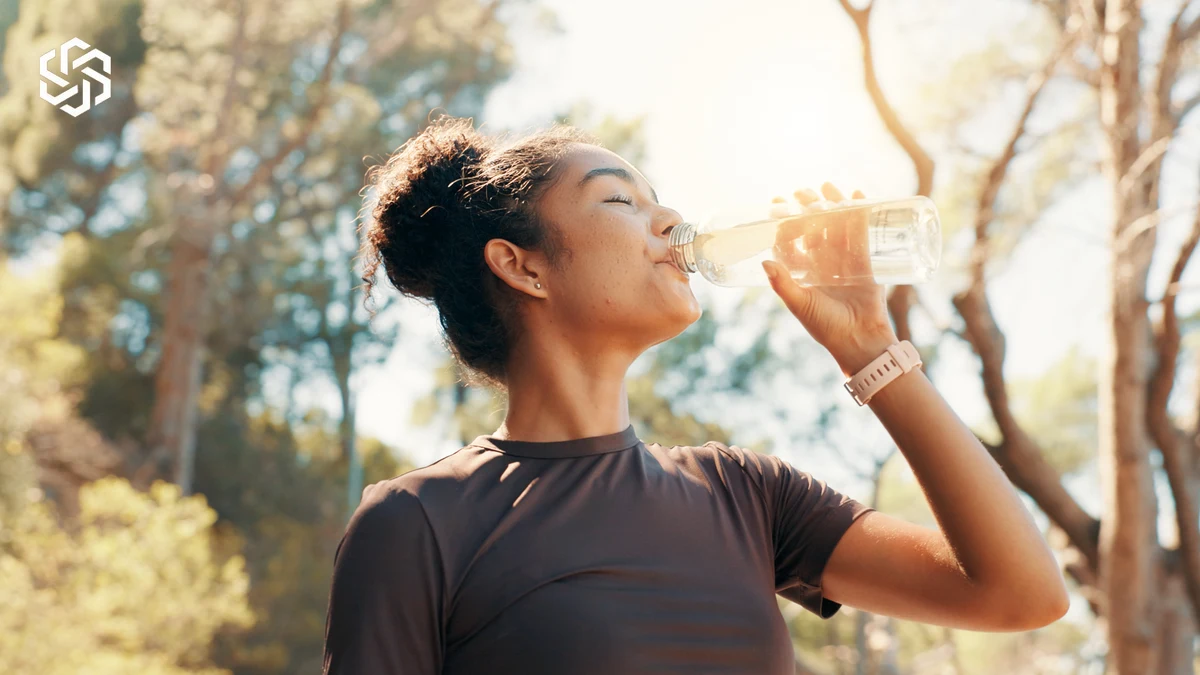 Woman drinking water outdoors after exercise