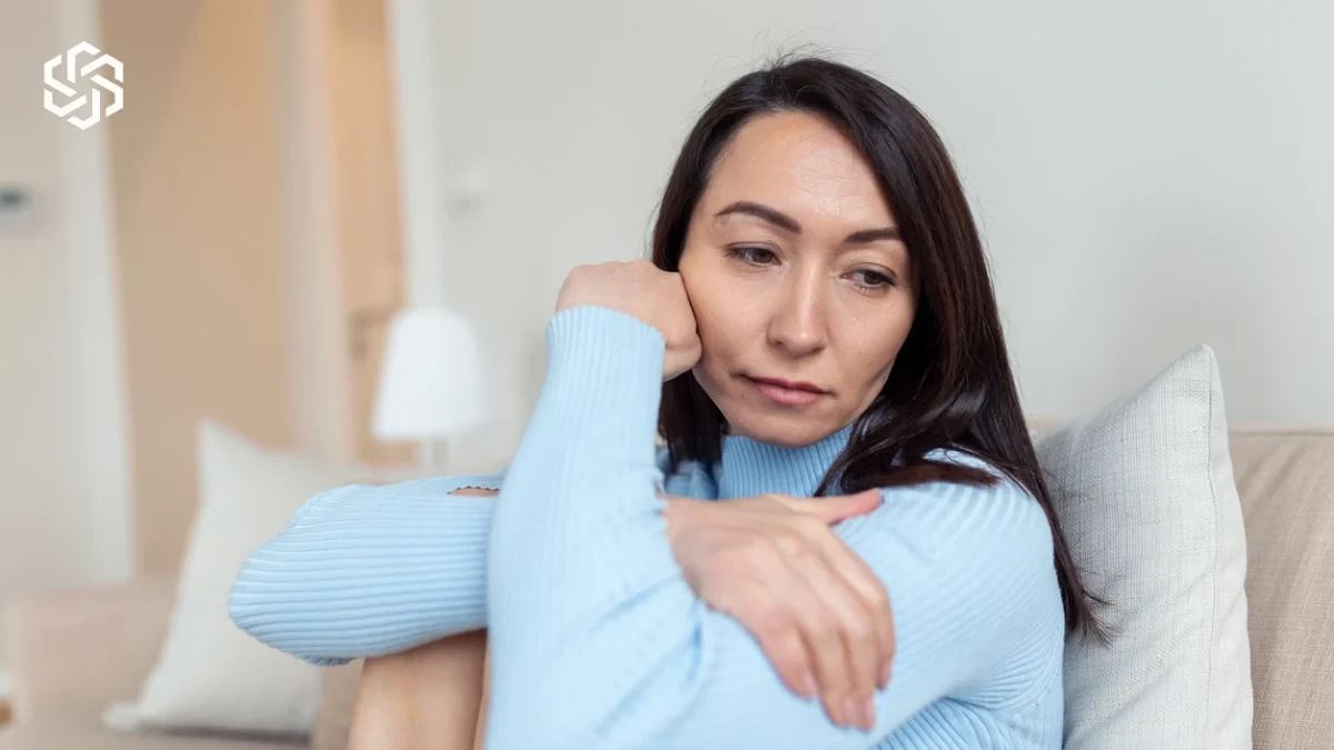 Tired woman resting on the couch, illustrating perimenopause vs. menopause symptoms