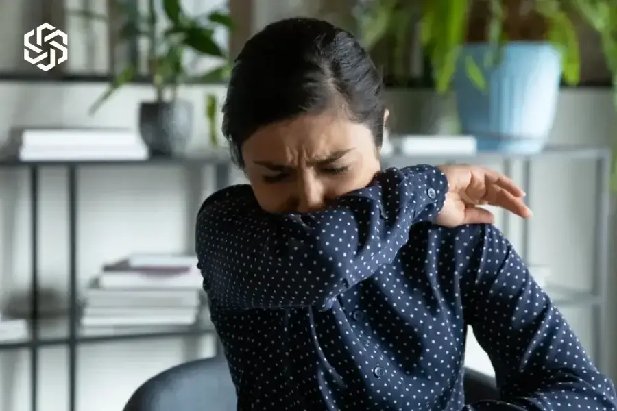 Woman coughing into her elbow at work