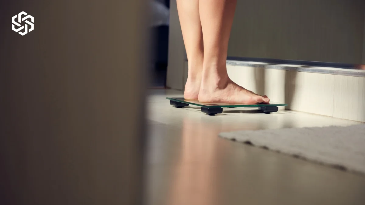 Woman stepping onto a bathroom scale to check for unexplained weight gain