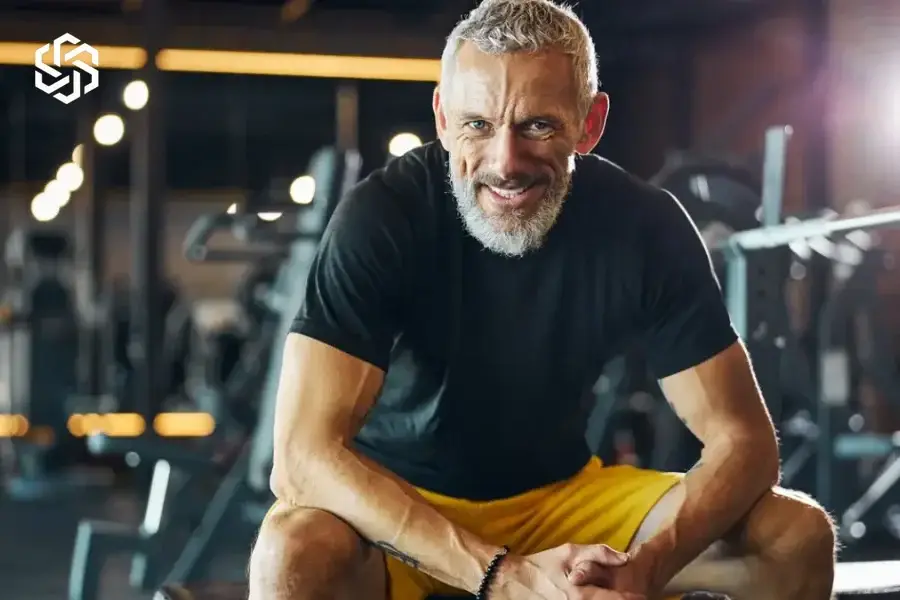 Smiling man resting on a weight bench at the gym