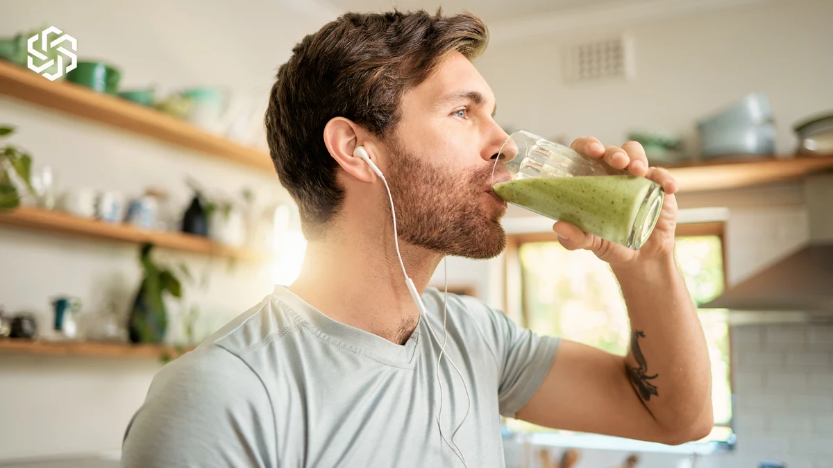 Man drinking a green smoothie in his kitchen