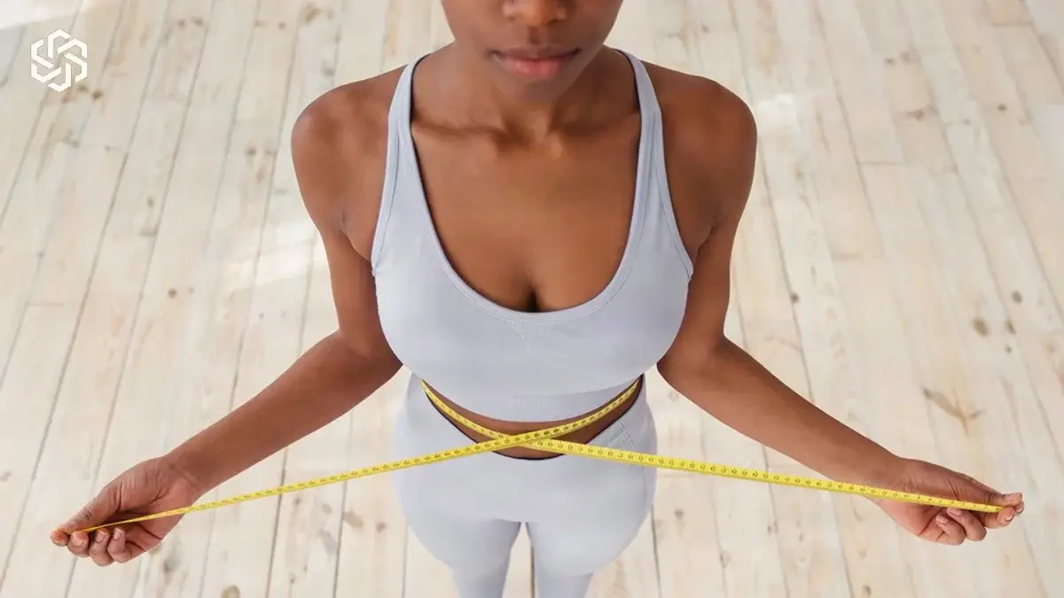 Woman measuring her waist with a tape measure