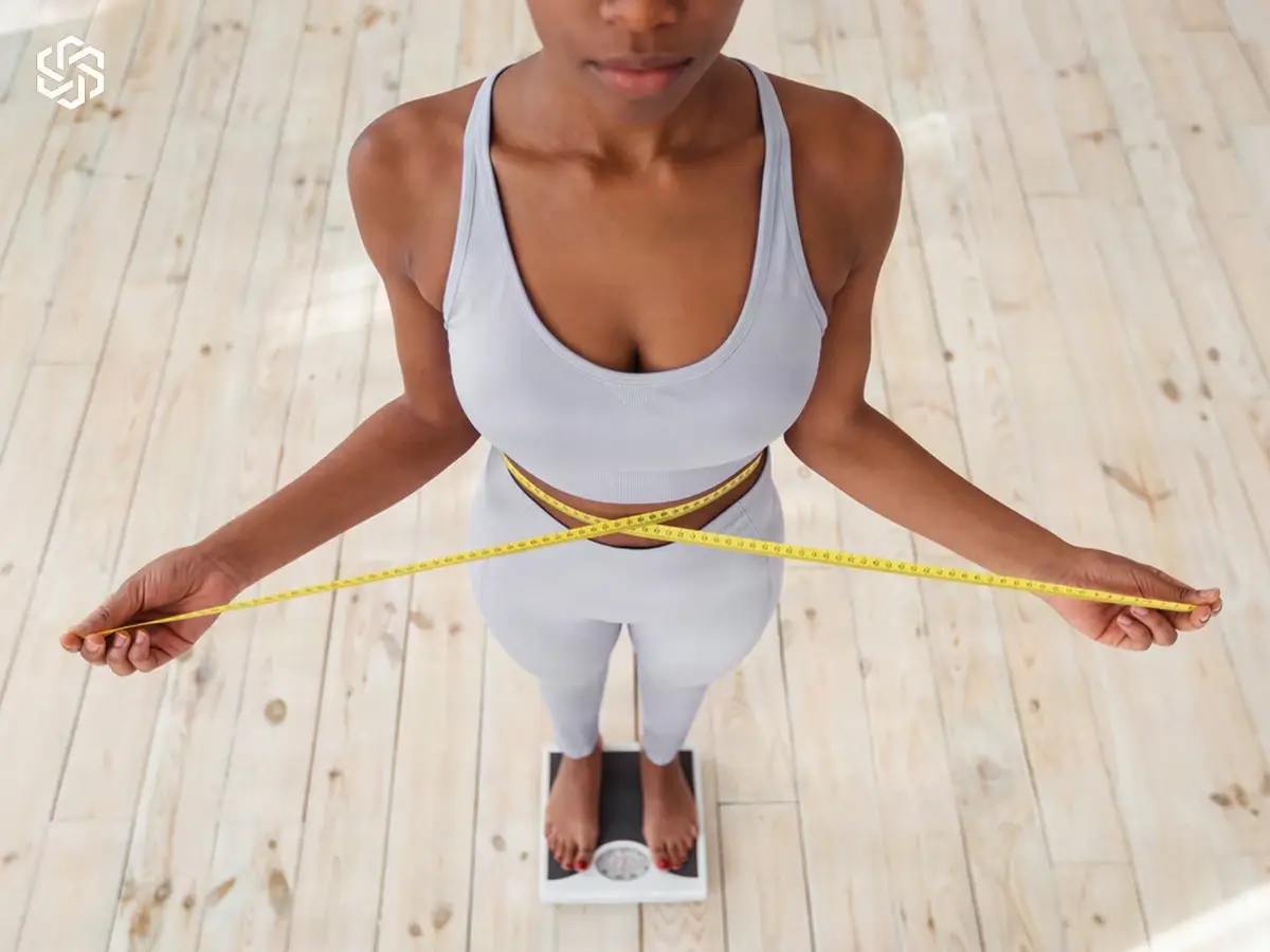 Woman measuring her waist with a tape measure, illustrating weight & metabolism questions